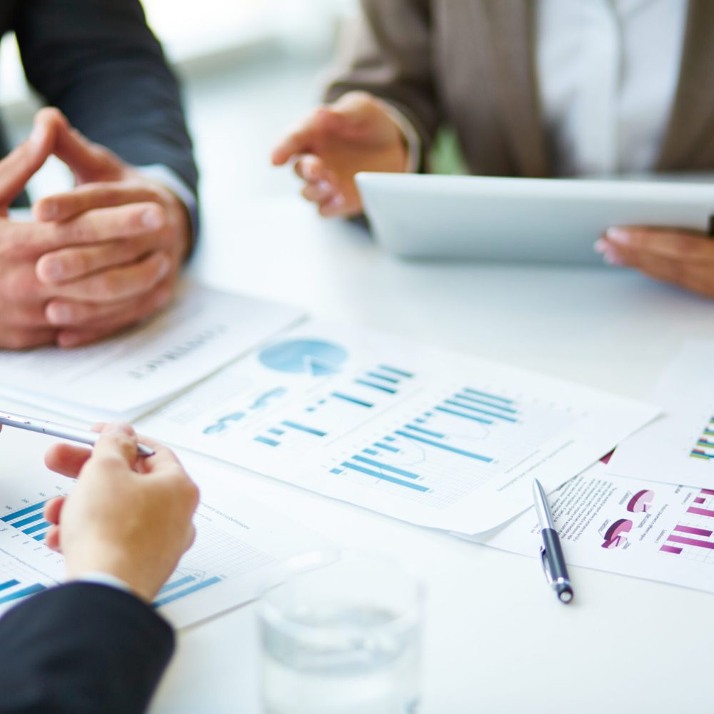 Image of business documents, pen and glasses on workplace during meeting of partners